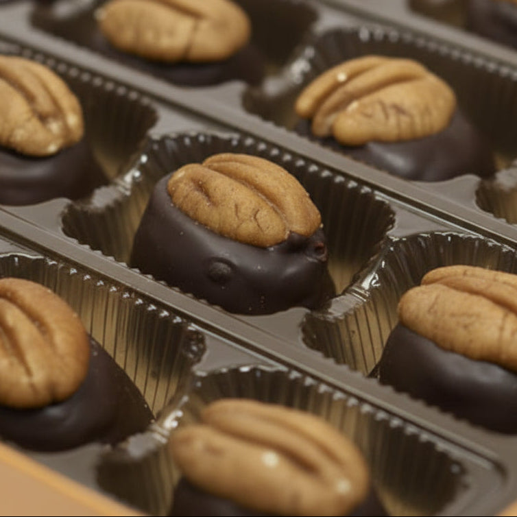 A close-up view of a single bourbon ball, highlighting the dark chocolate and pecan topping.