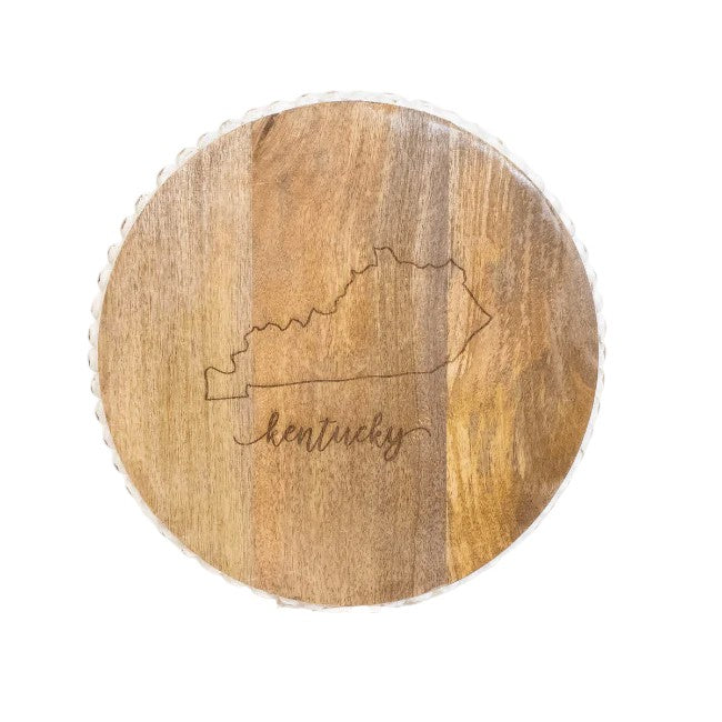 The decorative Kentucky serving board displayed on a kitchen shelf with other home decor.