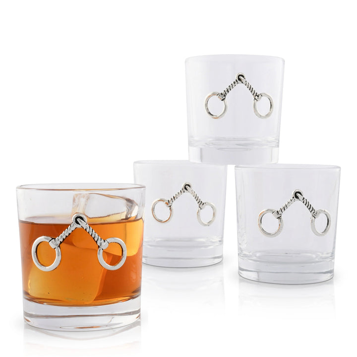 A set of four elegant 10 oz equestrian bit bar glasses, one filled with whiskey bourbon and ice.