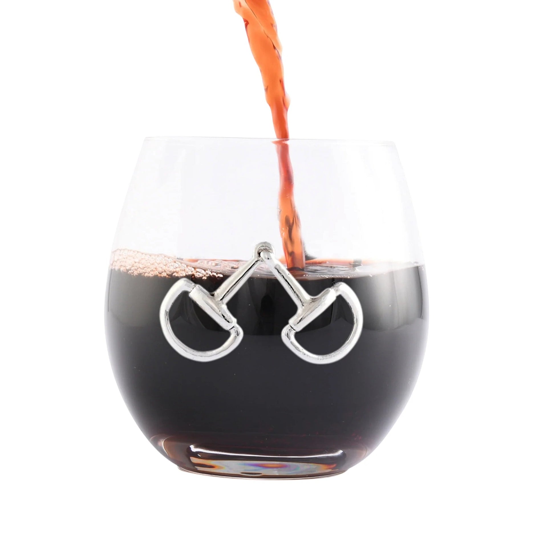 Glass with horse bit design being filled with a dark liquid on a white background