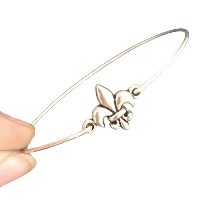A close-up image showing the intricate details of the silver-tone fleur de lis charm.
