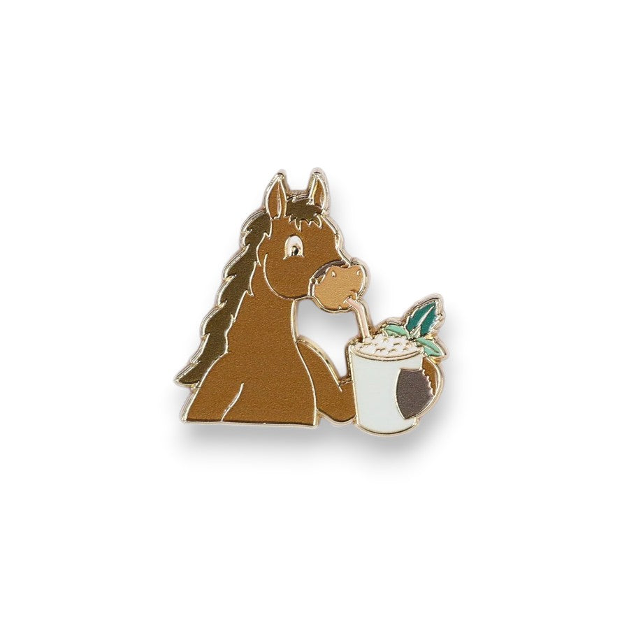 A whimsical enamel pin of a cartoon horse sipping a drink from a mug with a straw.