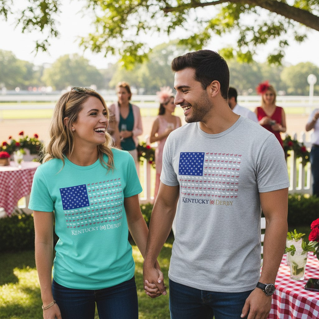 A smiling man and woman hold hands at a sunny racetrack, wearing the matching silver and celadon Kentucky Derby 152 horse flag shirts.