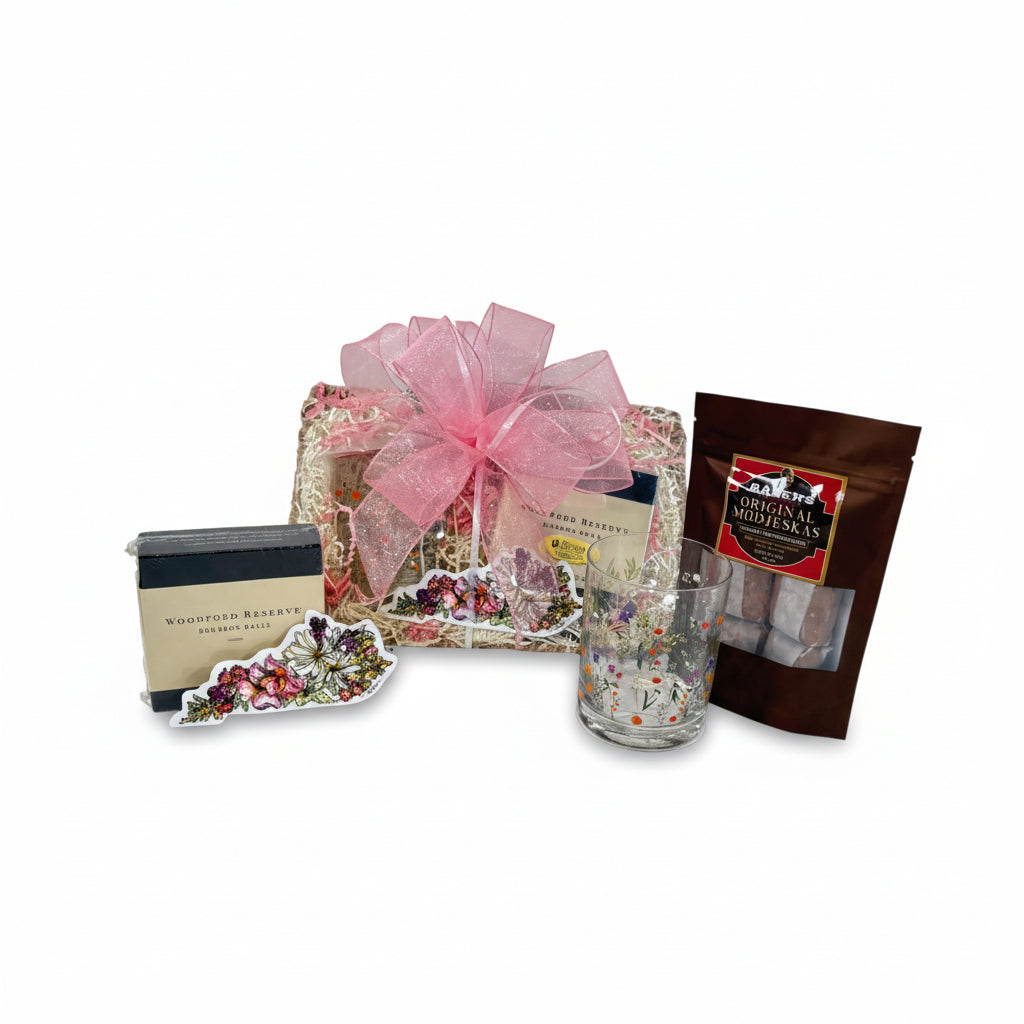 Gift basket with a pink bow, glass, and snacks on a white background