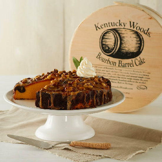 Bourbon barrel cake on a white stand with a wooden sign in the background