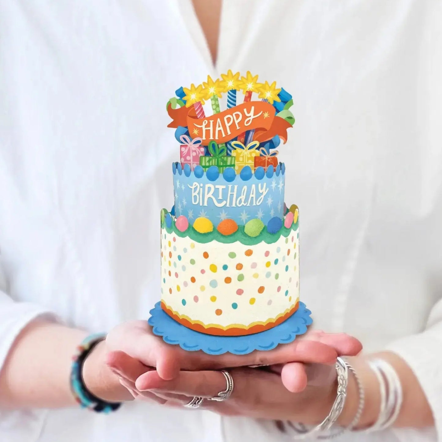Colorful birthday cake card held in hands with a plain background