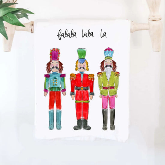 The colorful "Nutcracker Artwork" cotton tea towel, showcasing its classic holiday ballet design and 'falala la la la' text.