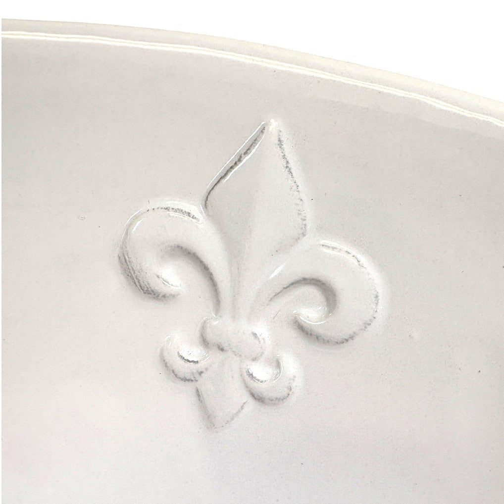 Close-up detail shot of the textured Fleur de Lis motifs on the edge of the serving bowl.