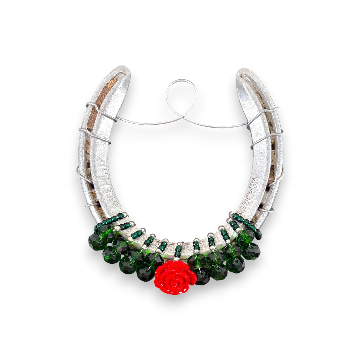 A close-up of the bejeweled horseshoe featuring a gold horsehead charm and a single red rose.