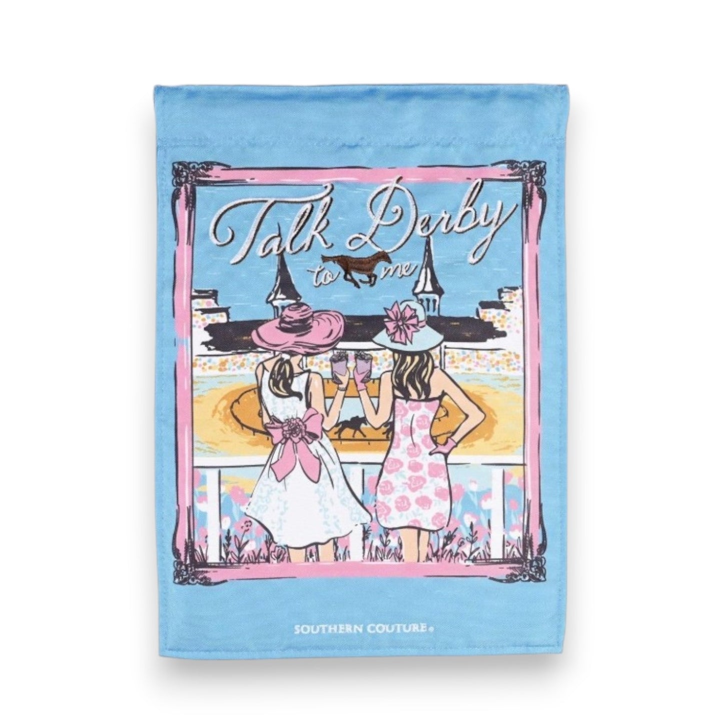 A light blue Southern Couture garden flag illustrating two fashionably dressed women in large hats toasting drinks at Churchill Downs, featuring a pink border and the white text "Talk Derby to me".