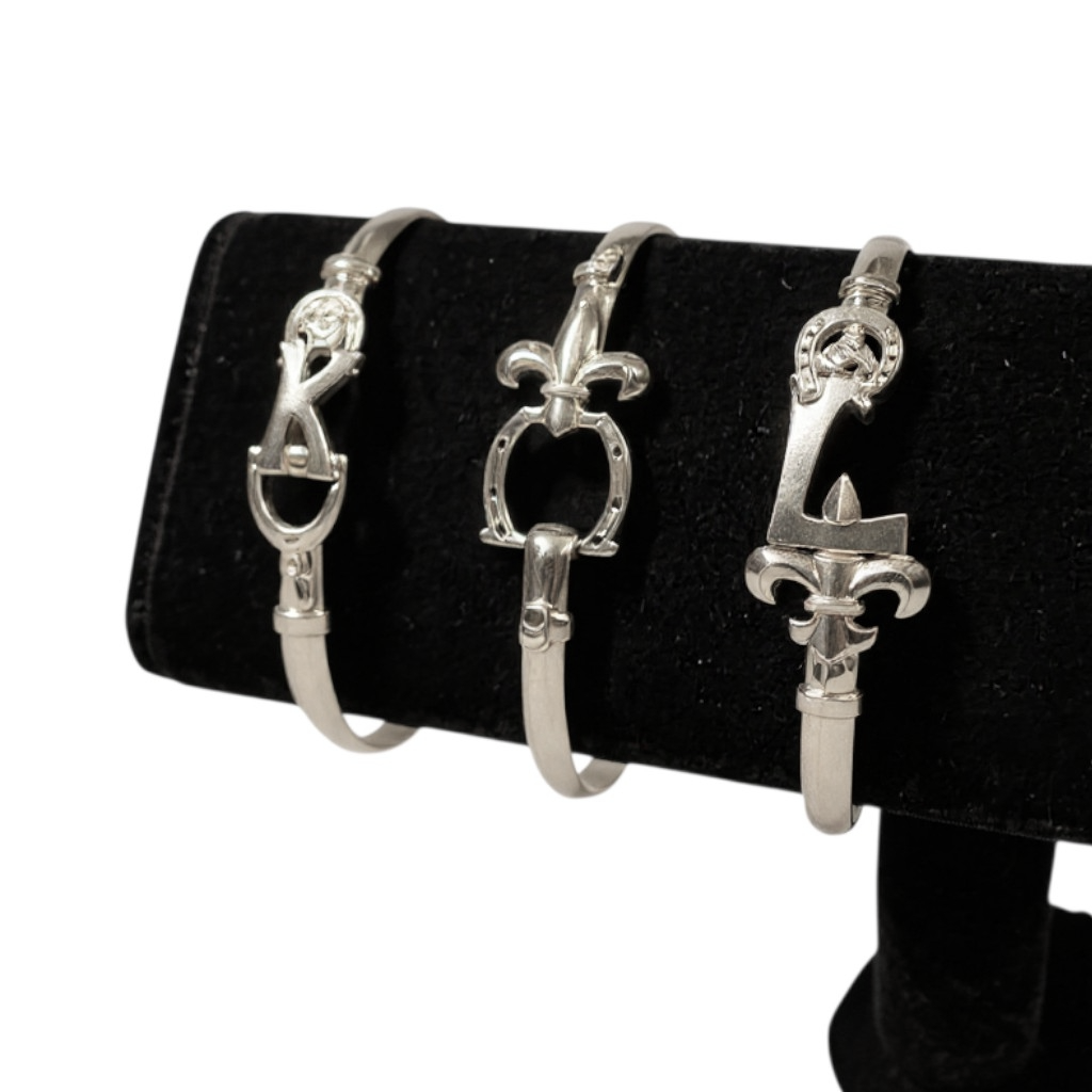 Three silver bracelet ends on a black stand with a white background