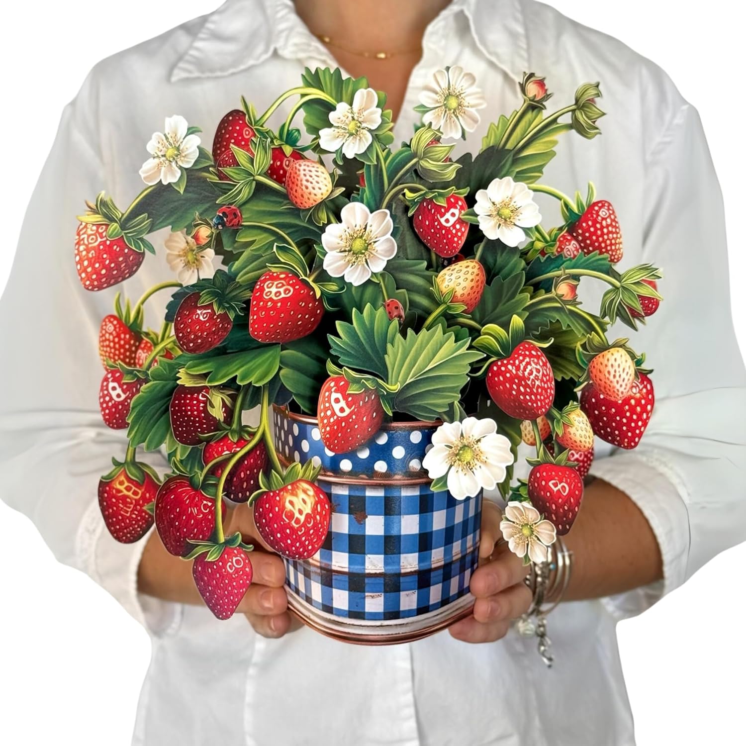 Person holding a decorative arrangement of strawberries and flowers in a blue and white checkered pot.