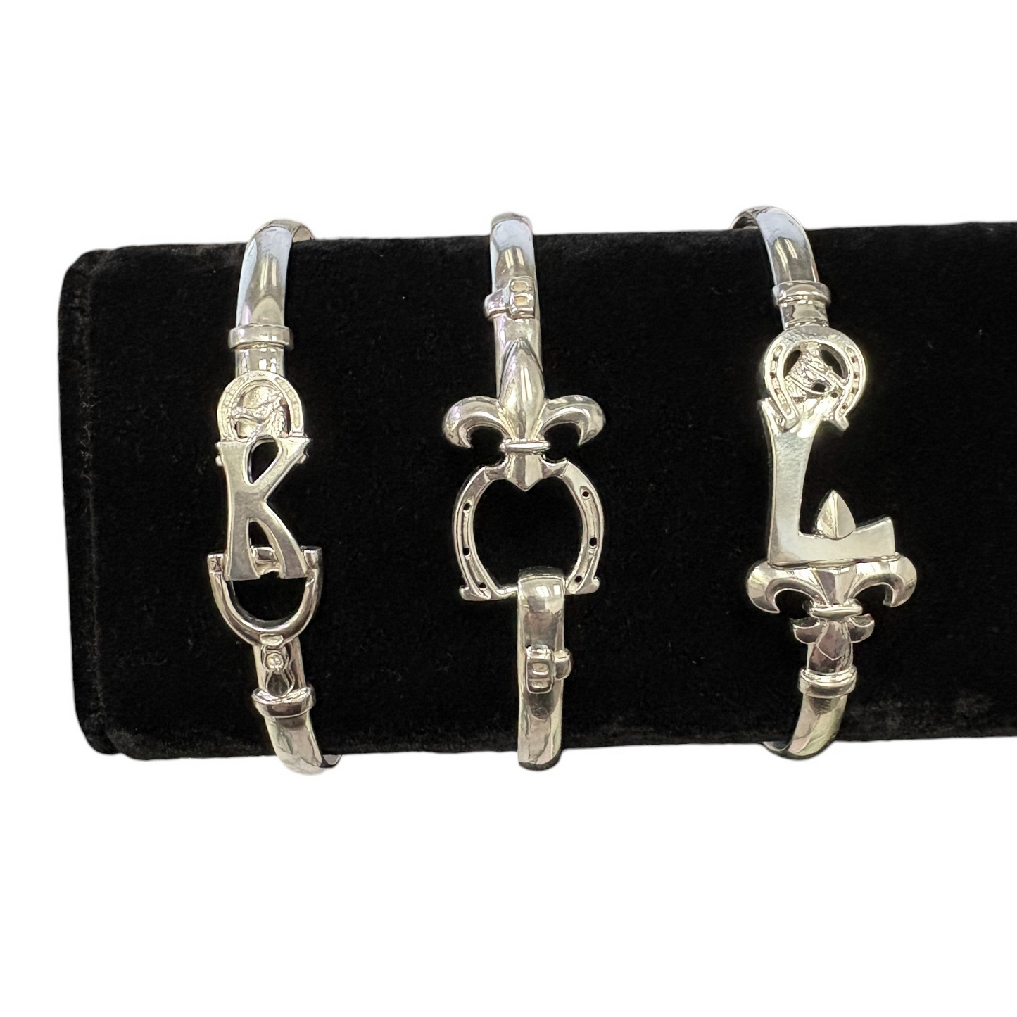 A collection of three distinct sterling silver equestrian bracelets on a display.