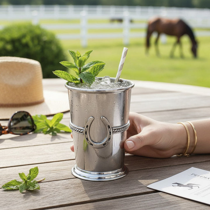 A Kentucky Mint Julep being enjoyed on a back porch with horses in the distance grazing.