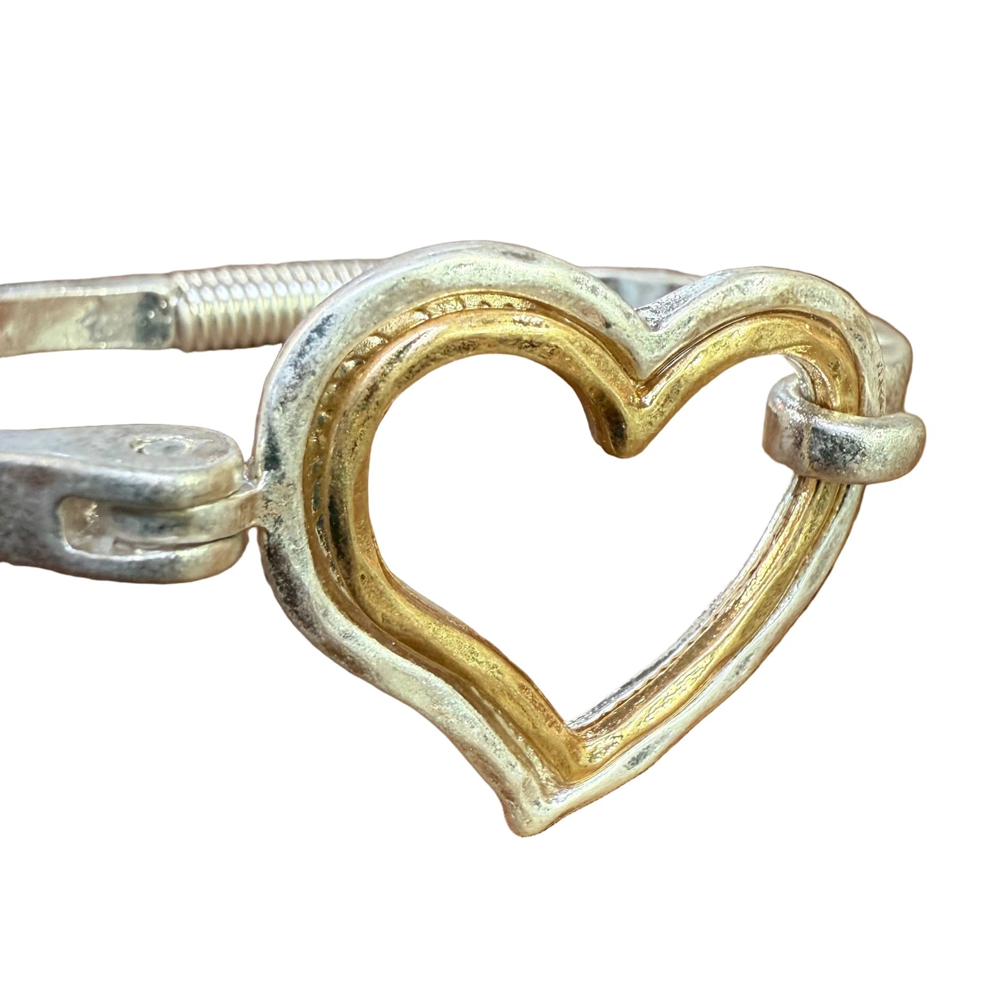 Heart-shaped object with gold and silver finish on a wooden surface