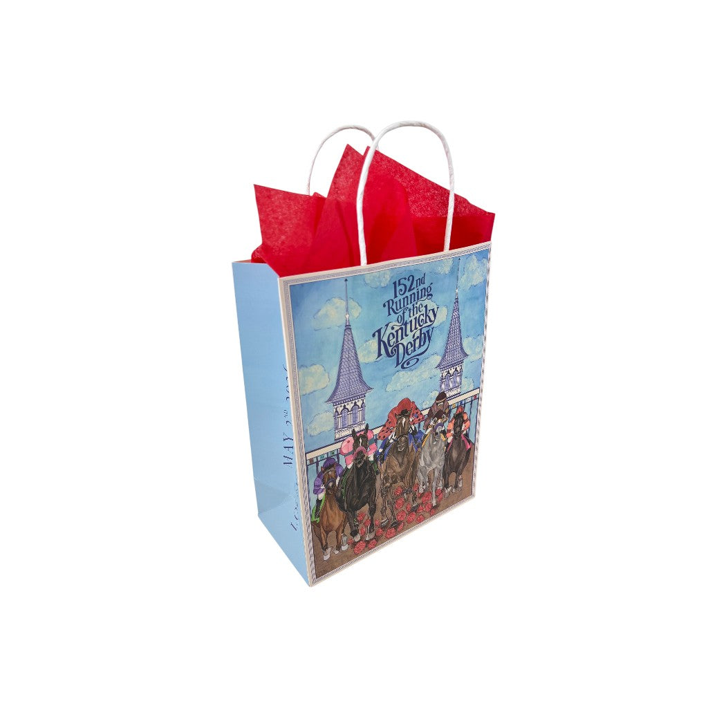 An angled view of the 152nd Kentucky Derby gift bag, showcasing the front race day illustration, white rope handles, and overflowing red tissue paper.