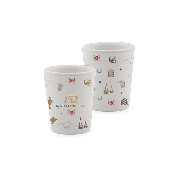Two white ceramic 1.75 oz shot glasses featuring the 152nd Kentucky Derby text and a wrap-around pattern of gold and red racing icons, including jockey silks, the twin spires, and mint julep cups.