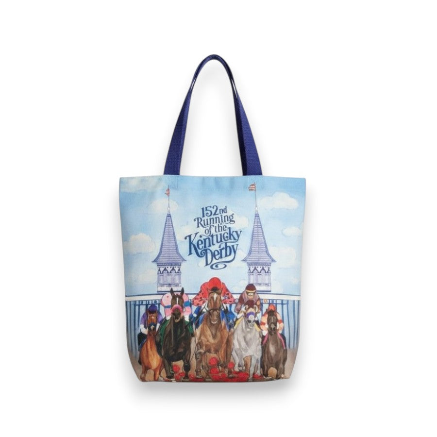 A commemorative 152nd Kentucky Derby tote bag featuring contrasting navy blue handles and a colorful graphic of racehorses running in front of historic grandstand spires under a blue sky.
