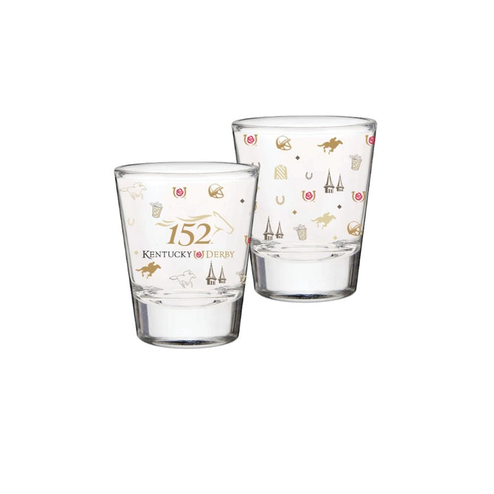 Two clear 1.75 oz shot glasses on a white background, featuring a white and golden wrap-around pattern of Kentucky Derby icons like jockey silks, twin spires, and roses.