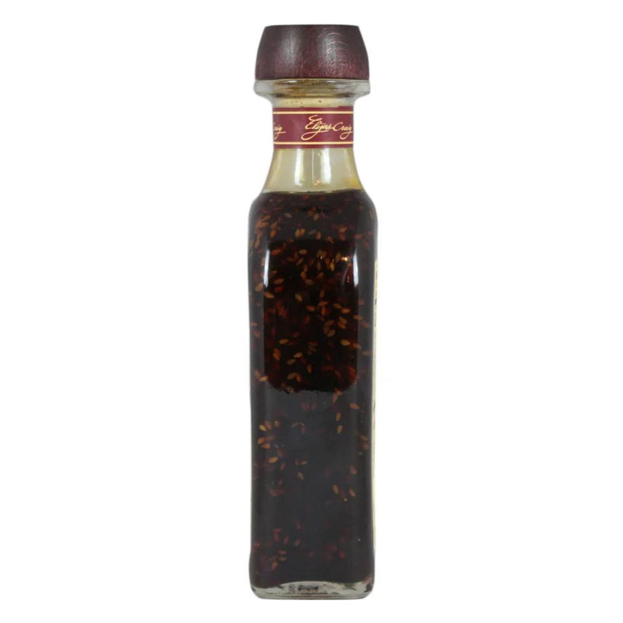 Bottle of dark liquid with a red cap on a white background