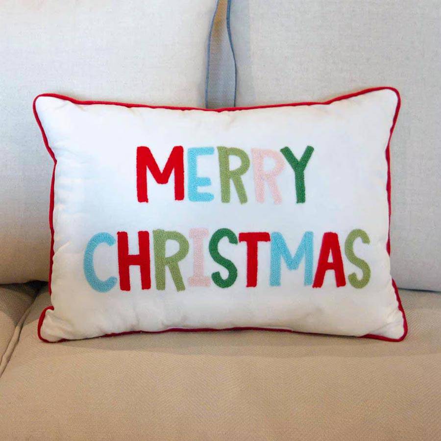 white rectangle pillow with multi-colored 'Merry Christmas' text and red edge trim