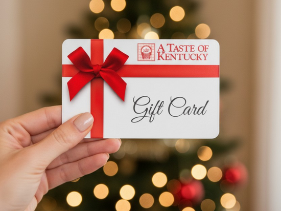 The A Taste of Kentucky E-Gift Card with red ribbon held in front of a blurred Christmas tree