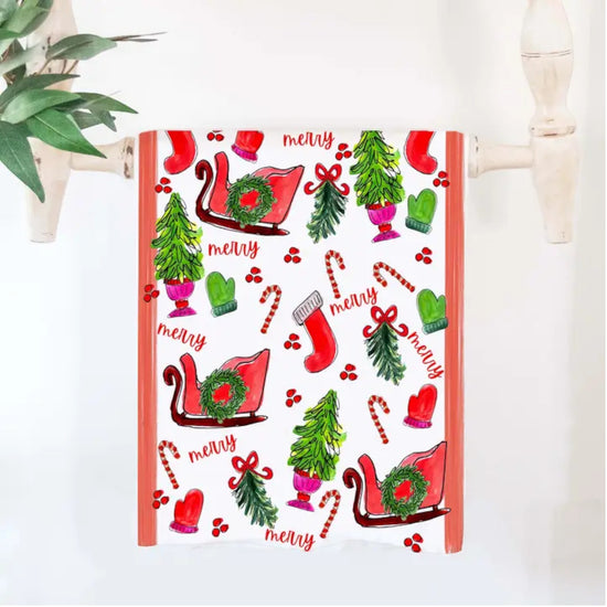 A close-up of the "All Things Christmas" cotton tea towel, featuring whimsical holiday illustrations.