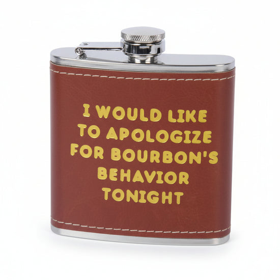 Close-up of the "Apologize for Bourbon's Behavior" flask with gold foil text on black faux leather.