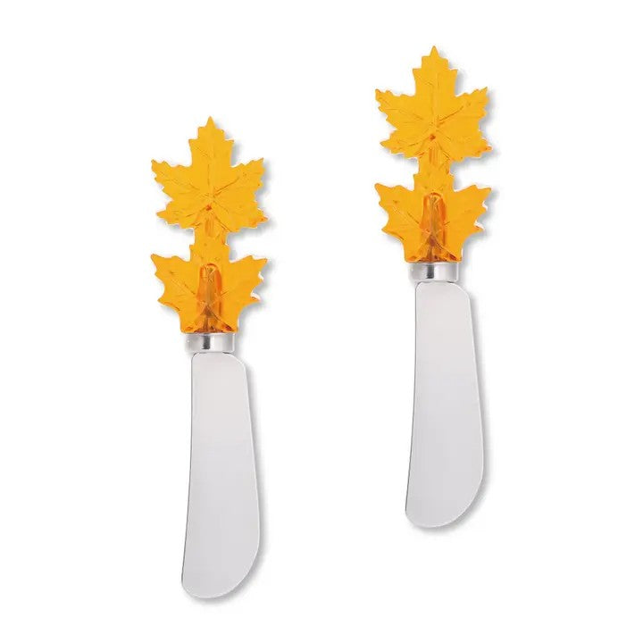 Two butter cheese spreader knives with yellow leaf-shaped ends on a white background