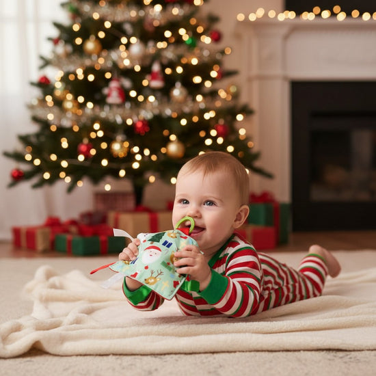 A baby during tummy time, reaching for the festive crinkle toy in front of them.