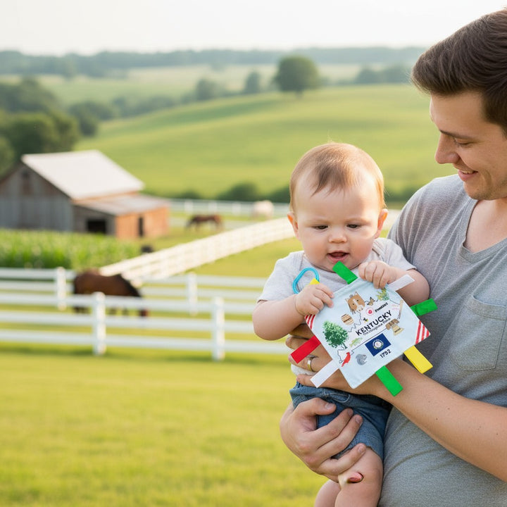 A happy baby, holding the Kentucky-themed crinkle tag toy.