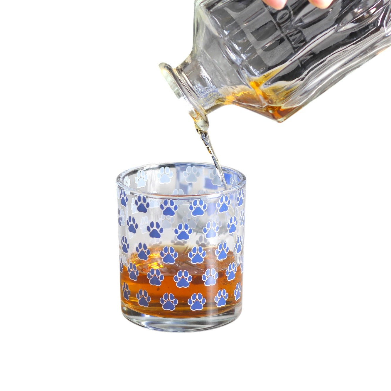 Glass being filled with a clear liquid, likely whiskey, on a white background