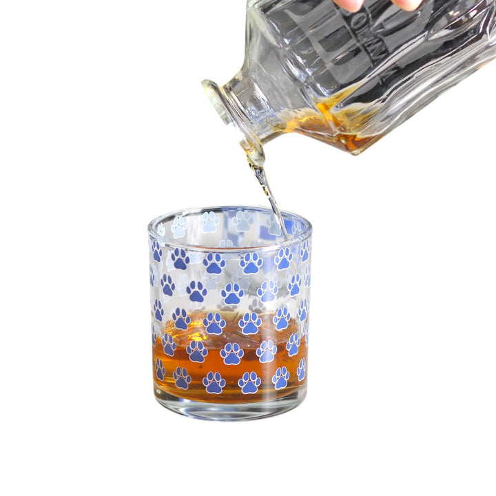 Glass being filled with a clear liquid, likely whiskey, on a white background
