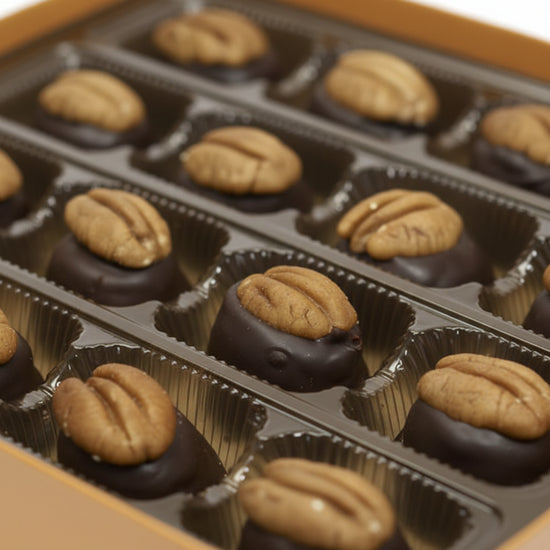 A close-up view of a single bourbon ball, highlighting the dark chocolate and pecan topping.