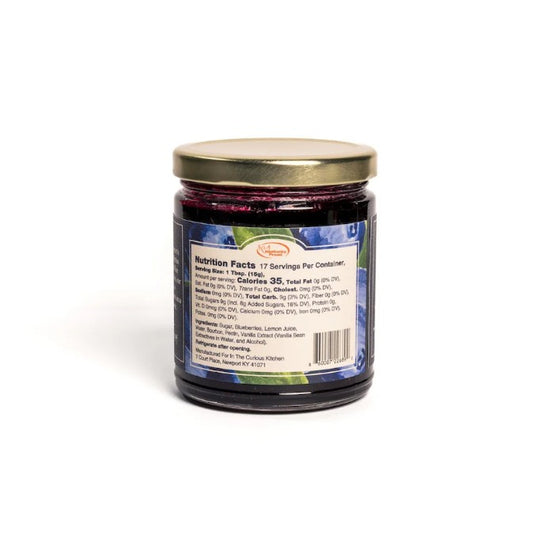 The back label of the Bourbon Blueberry Jam jar showing nutrition facts, ingredients, and the In the Curious Kitchen logo.