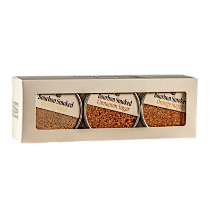 A white gift box containing three tins of Bourbon Smoked Sugars: Orange, Vanilla, and Cinnamon.