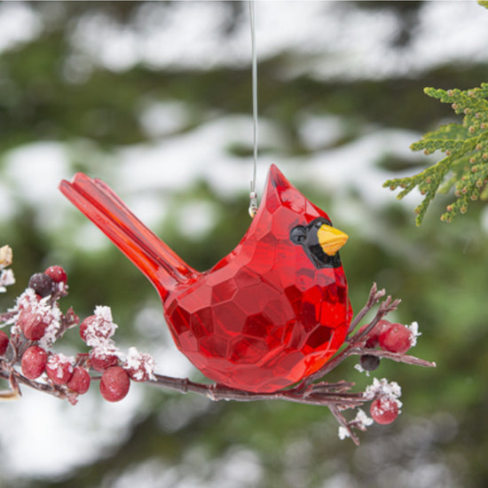 A close-up lifestyle shot of the red cardinal ornament nestled in evergreen.