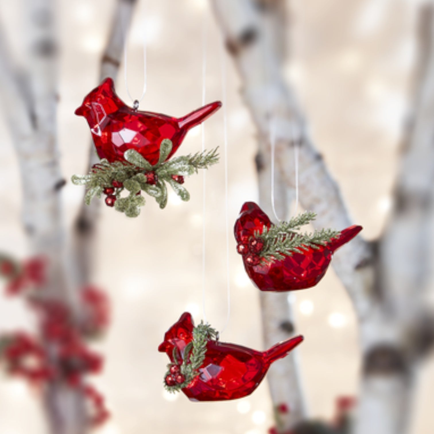 Red bird-shaped Christmas ornaments with greenery against a blurred natural background