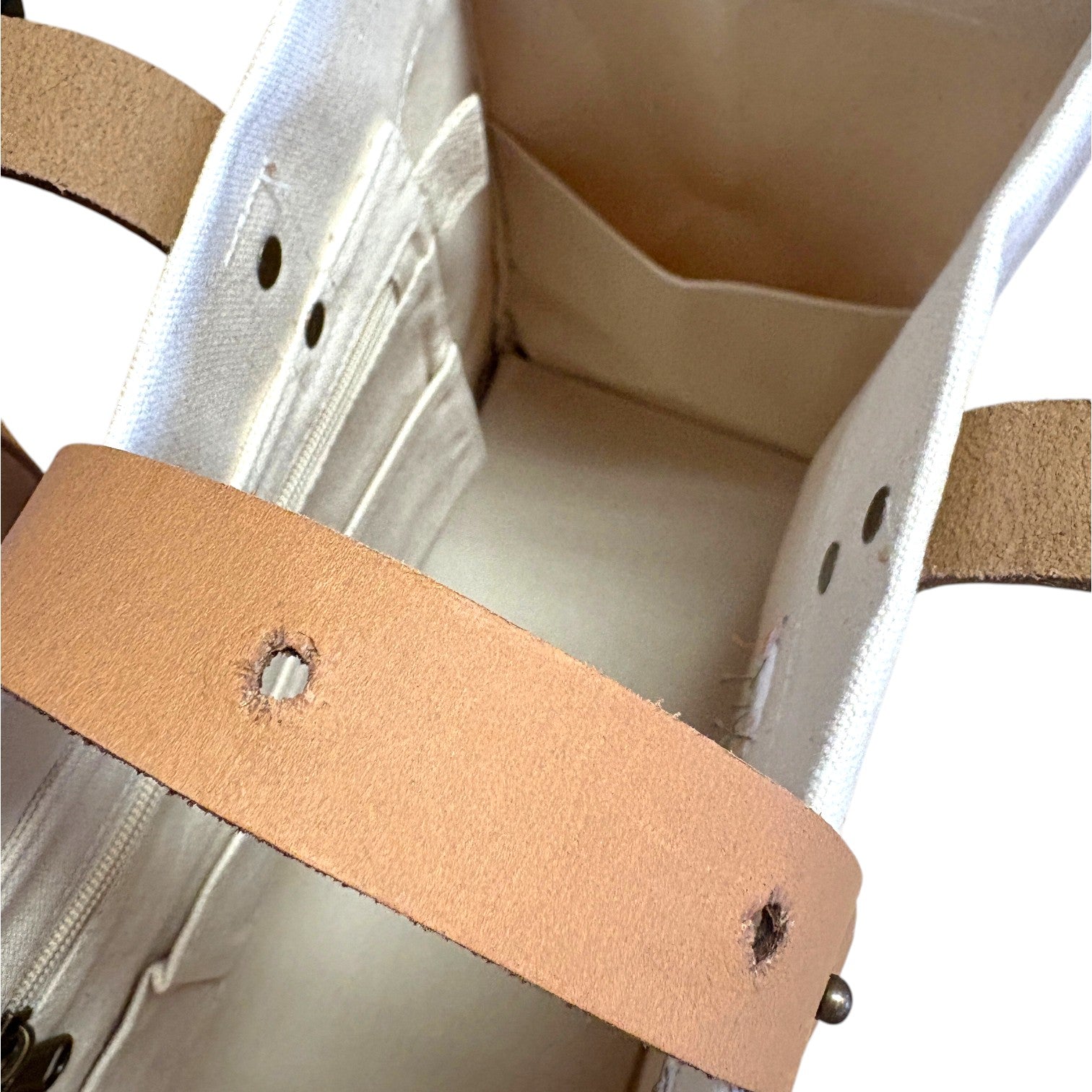  Detail shot of the bag's interior, showcasing the durable canvas, thick leather handles, and adjustable brass stud closure.