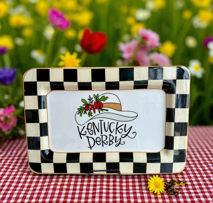 Decorative tray with 'Kentucky Derby' design on a checkered tablecloth with flowers in the background