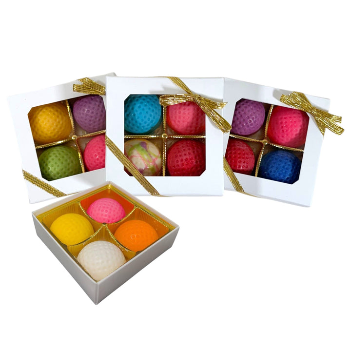 Colorful chocolate golf balls in a white box with gold ribbon on a white background