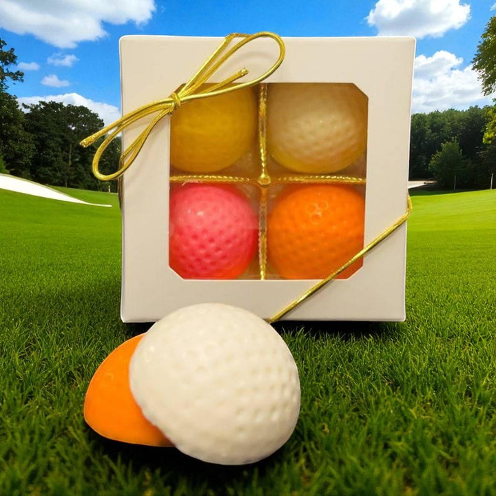 Set of colorful chocolate golf balls in a box on a grassy field with a blue sky.
