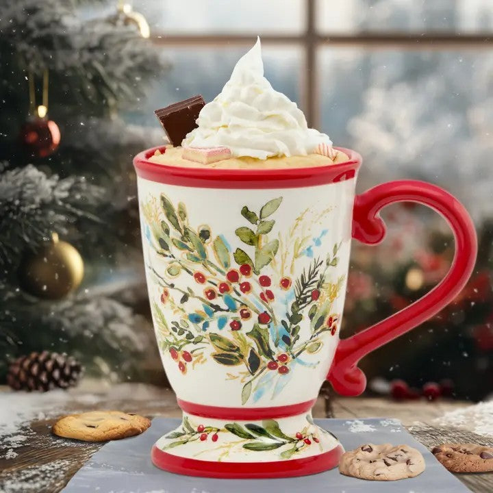 Decorative mug with floral design filled with hot chocolate and whipped cream, Christmas tree in the background