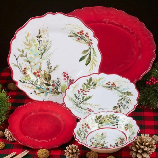Set of Christmas-themed plates and bowls on a plaid tablecloth with pine cones and evergreen branches.