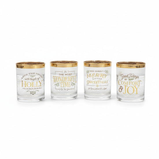 A group of four Christmas-themed glasses with gold rims and lettering.