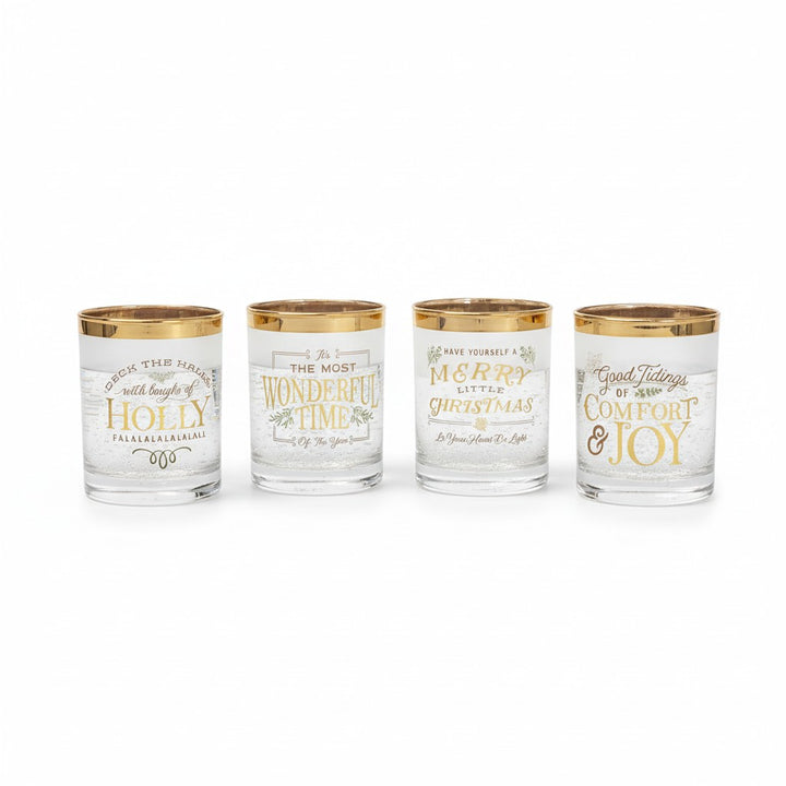 A group of four Christmas-themed glasses with gold rims and lettering.