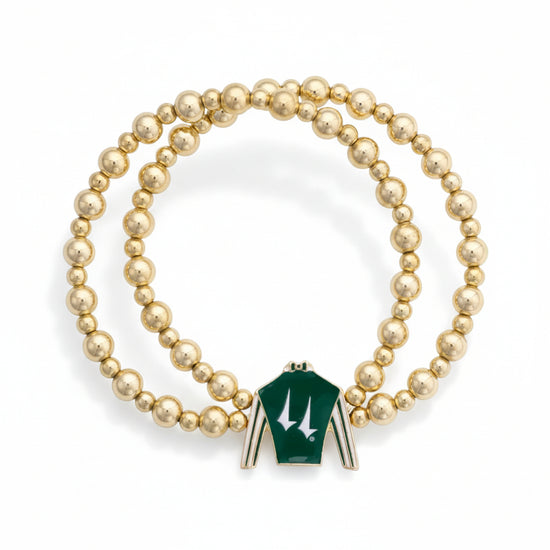  Full view of the Churchill Downs two-row gold bead stretch bracelet, showcasing the green and white jockey silk enamel charm against a white background.