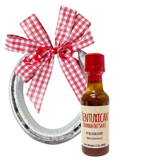  Authentic Churchill Downs horseshoe topped with a mini bottle of Kentuxican' Bourbon Hot Sauce, tied with a gingham bow on a white background.