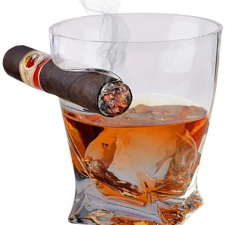 Cigar resting on a glass of whiskey with ice cubes on a white background