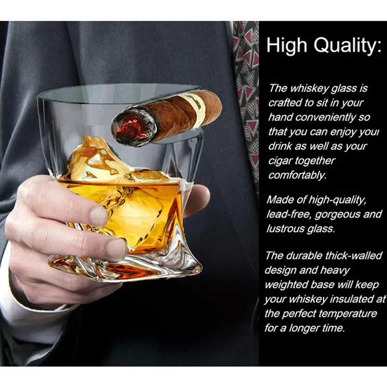 A person holding the Cigar Whiskey Glass, with a lit cigar resting in the built-in holder and amber whiskey in the glass.